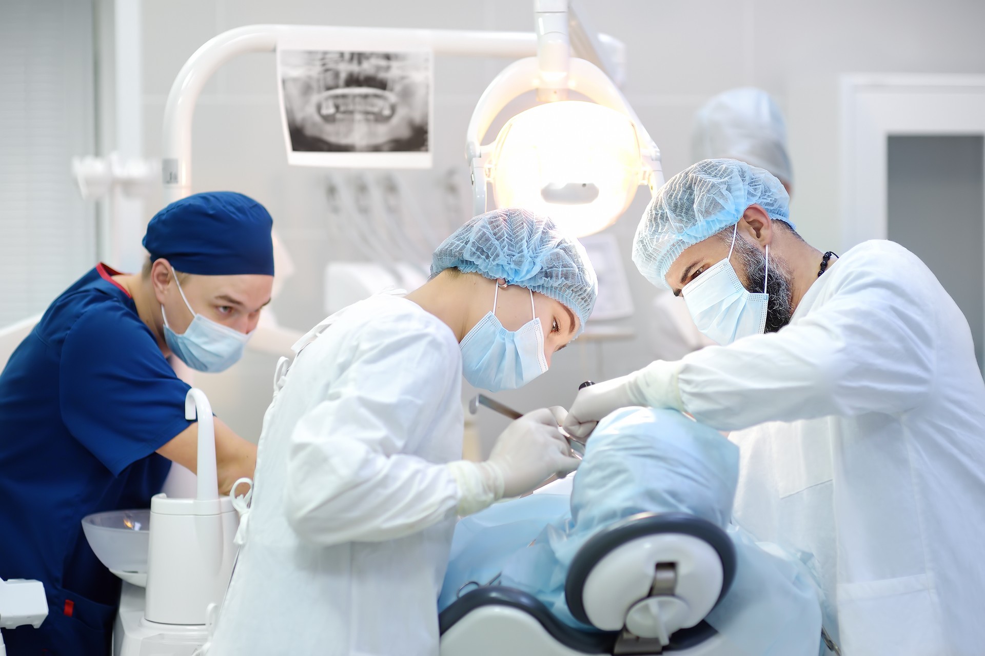 Chirurg und Krankenschwester während einer Zahnoperation. Anästhesierter Patient im Operationssaal. Einsatz von Zahnimplantaten in der Klinik.